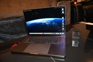 MacBook Pro 16-inch (M3 Max, 2023) on a reflective coffee table with the display on and facing you